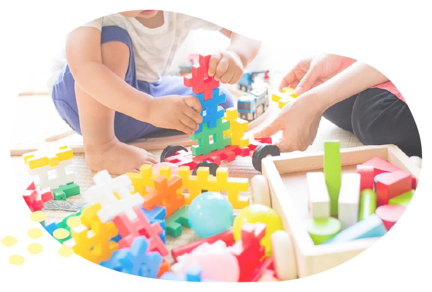 スタッフと子どもが一緒にブロック遊びをして笑顔で触れ合う様子