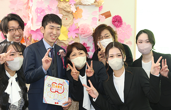 桜の装飾の前で仲良くピースサインをして記念撮影をするスタッフたち