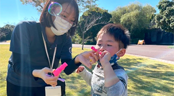 公園で子どもとシャボン玉遊びをして寄り添うスタッフの様子